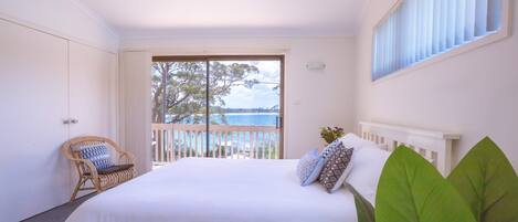 Ein Schlafzimmer mit einem großen Bett, einem Sessel und einem Balkon mit Meerblick.