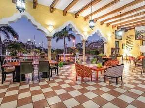 An outdoor dining area with checkered flooring, tables, and chairs. - Hotel Hacienda Sanchez (Valladolid)