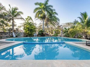 Une piscine entourée de palmiers et bordée d’un mur de pierre.