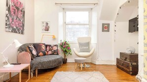 A cozy living room with a sofa, a chair, a small table, a potted plant, and a window with a view. - Stunning Apartment in Royal Mile (Edinburgh)