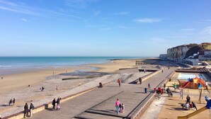 A beach with a wooden boardwalk, a playground, and a cliff in the background. - Charming fisherman's house near the beach and the village center (Veules-les-Roses)