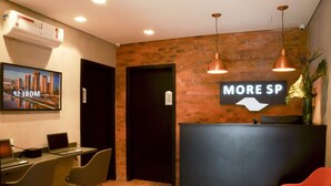 A reception area with a brick wall, a black reception desk, and a sign reading "MORE SP". - Hostel More SP (São Paulo)