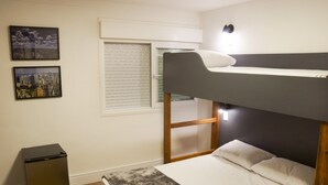 A bunk bed room with a cityscape view, a small fridge, and a window with blinds. - Hostel More SP (São Paulo)
