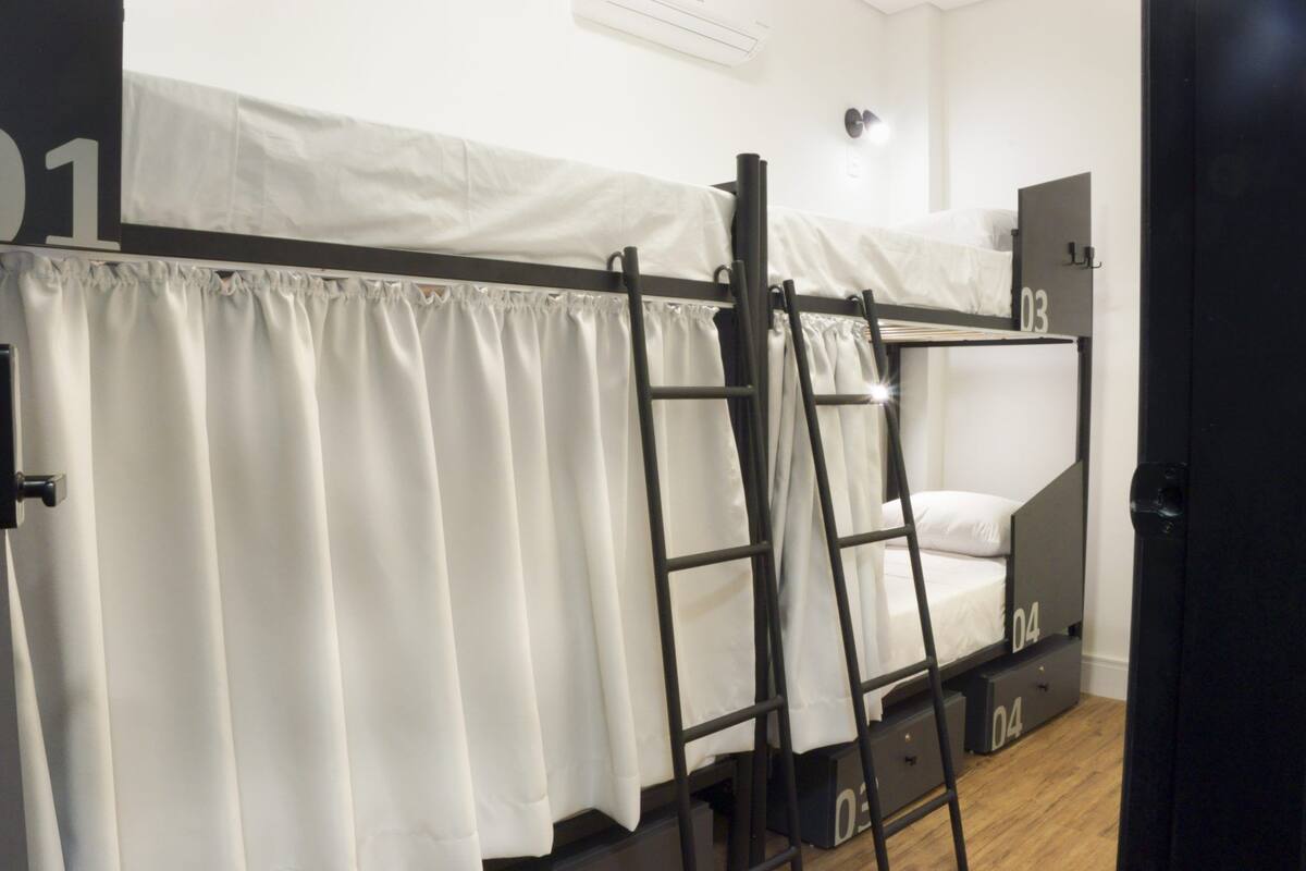 A bunk bed with a ladder, numbered compartments, and a curtain.