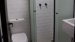 A bathroom with a white toilet, a glass shower enclosure, and a sink with a marble countertop. - Hostel More SP (São Paulo)