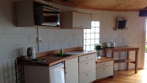 Una cocina compacta con refrigerador, lavamanos y ventana.