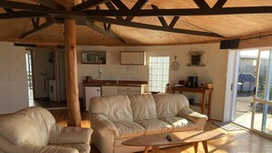 Una sala de estar acogedora con techo de madera, un sofá, una mesa de centro y una cocina al fondo.