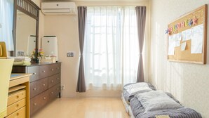 Un dormitorio con cama, cómoda, espejo y un tablón de anuncios con un letrero de bienvenida.
