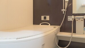 Un baño moderno con una bañera blanca, cabina de ducha y panel de control en la pared.