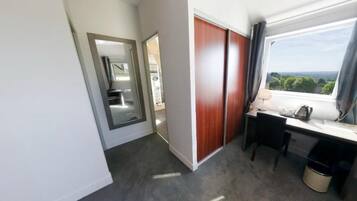 Hotelkamer met een bureau, een stoel, een raam met uitzicht, een kledingkast en een spiegel.