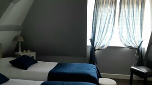 Egy szállodai szoba, amelyben két ágy, egy szék, egy éjjeliszemélyzet és egy lámpa található.