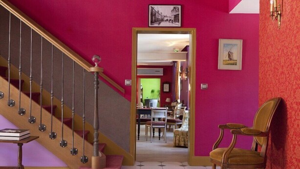 A staircase with a wooden handrail and a pink wall. - Logis DU Commerce (Oucques-la-Nouvelle)
