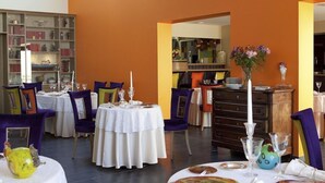 A dining area with round tables, chairs, and a bookshelf. - Logis DU Commerce (Oucques-la-Nouvelle)