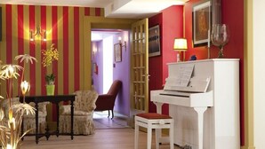 A room with a piano, a table with chairs, a lamp, and a door leading to another room. - Logis DU Commerce (Oucques-la-Nouvelle)