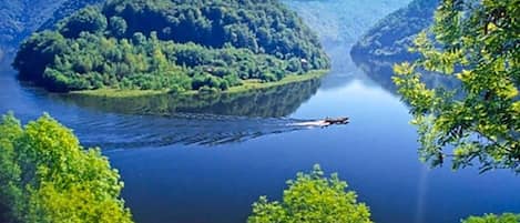A river with a boat, surrounded by forested hills.