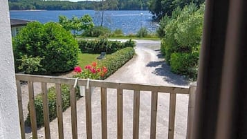 Ein Balkon mit Blick auf einen See, umgeben von Grün und einem Holenzaun.