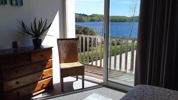 Un balcón con una silla de madera y un aparador, con vistas a un lago.