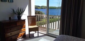 A balcony with a wooden chair and a dresser, overlooking a lake. - Hotel du Lac (Neuvic)