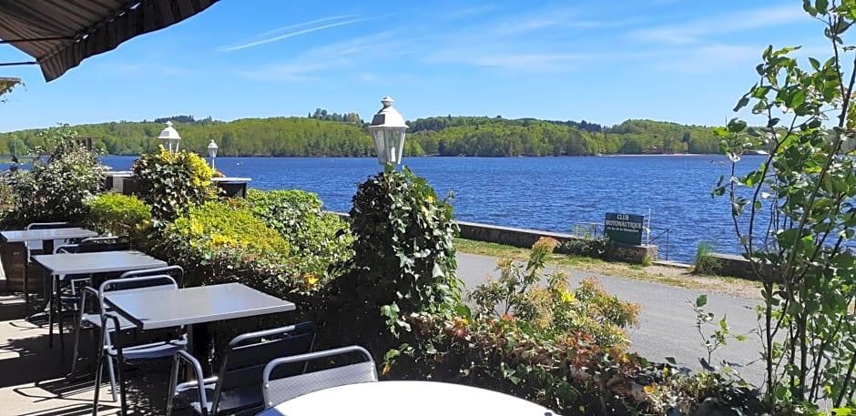 Un espacio al aire libre con mesas y sillas, con vista a un lago y una orilla boscosa.