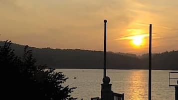 Un atardecer sobre un lago tranquilo con un muelle y un banco.