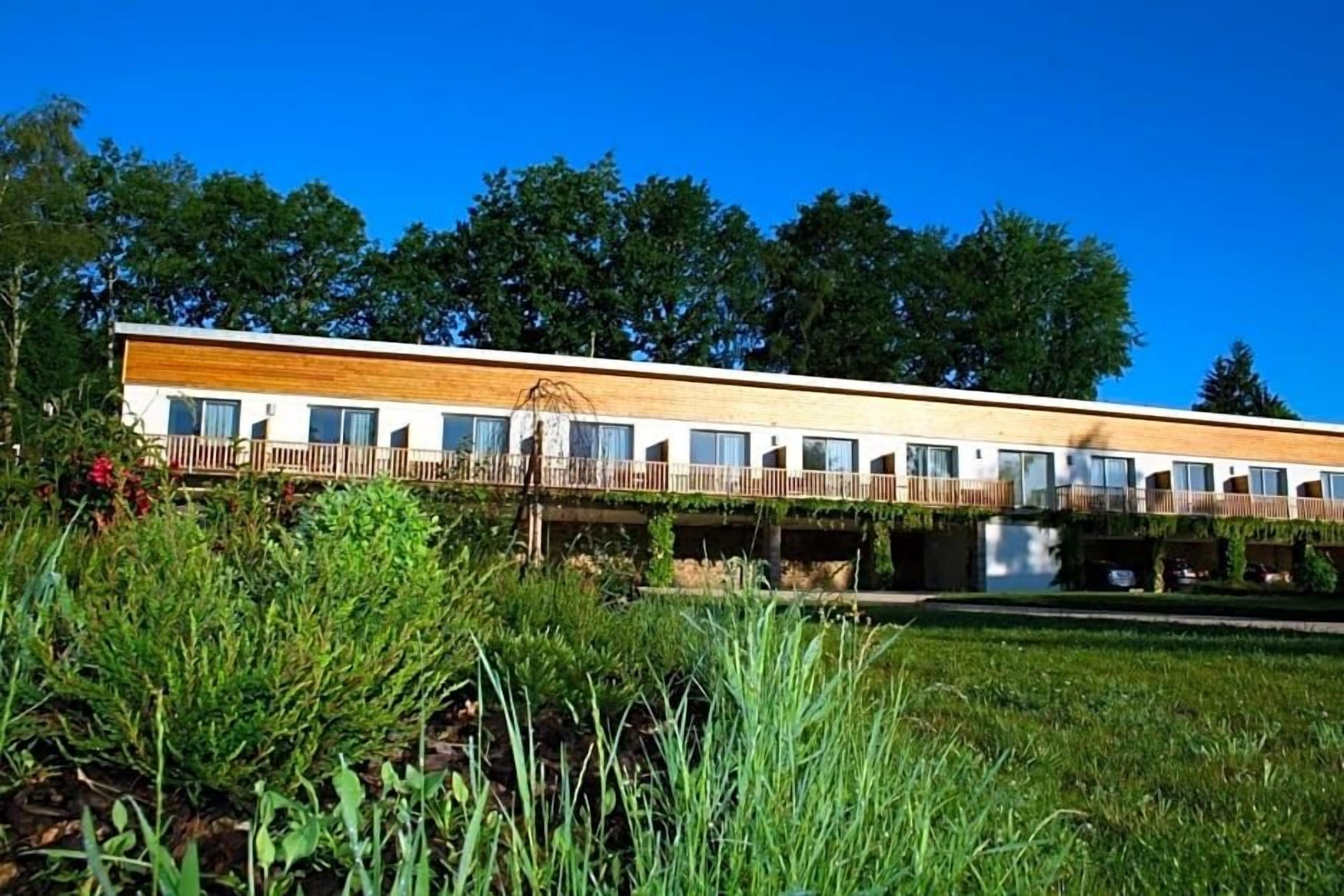 A modern building with a flat roof, multiple windows, and a wooden deck.