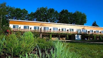 A modern building with a flat roof, multiple windows, and a wooden deck.