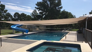 A swimming pool with a blue slide and a separate hot tub area. - Relax in your own secluded Yurt Cabin nestled into a 200+ acre Property! (Bastrop)