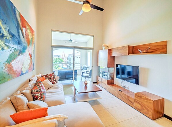 A modern living room with a sofa, coffee table, TV, and a large window.