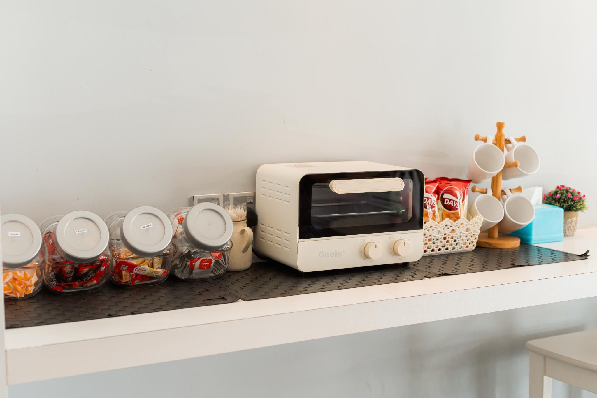 Una encimera de cocina con un tostador, frascos de comida y un soporte para tazas.