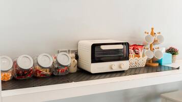 Una encimera de cocina con un tostador, frascos de comida y un soporte para tazas.
