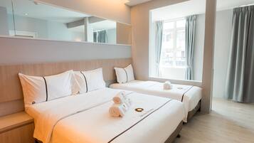 Een hotelkamer met twee bedden, een grote spiegel en een raam met gordijnen.