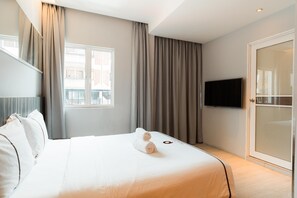 A hotel room with a bed, curtains, a television, and a sliding door. - Orange Premier Hotel Taman Segar (Kuala Lumpur)
