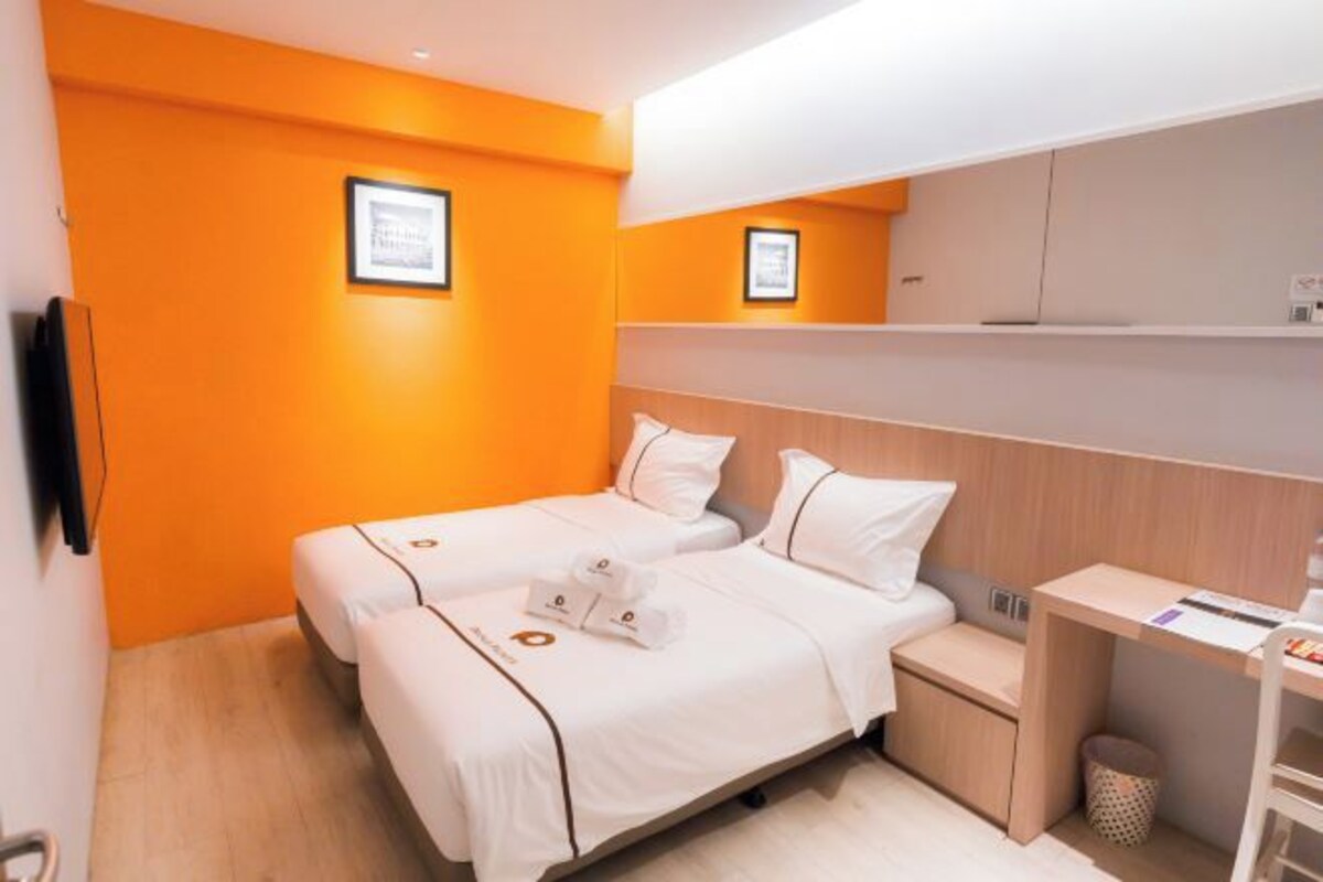 A hotel room with two beds, a desk, and a small seating area.