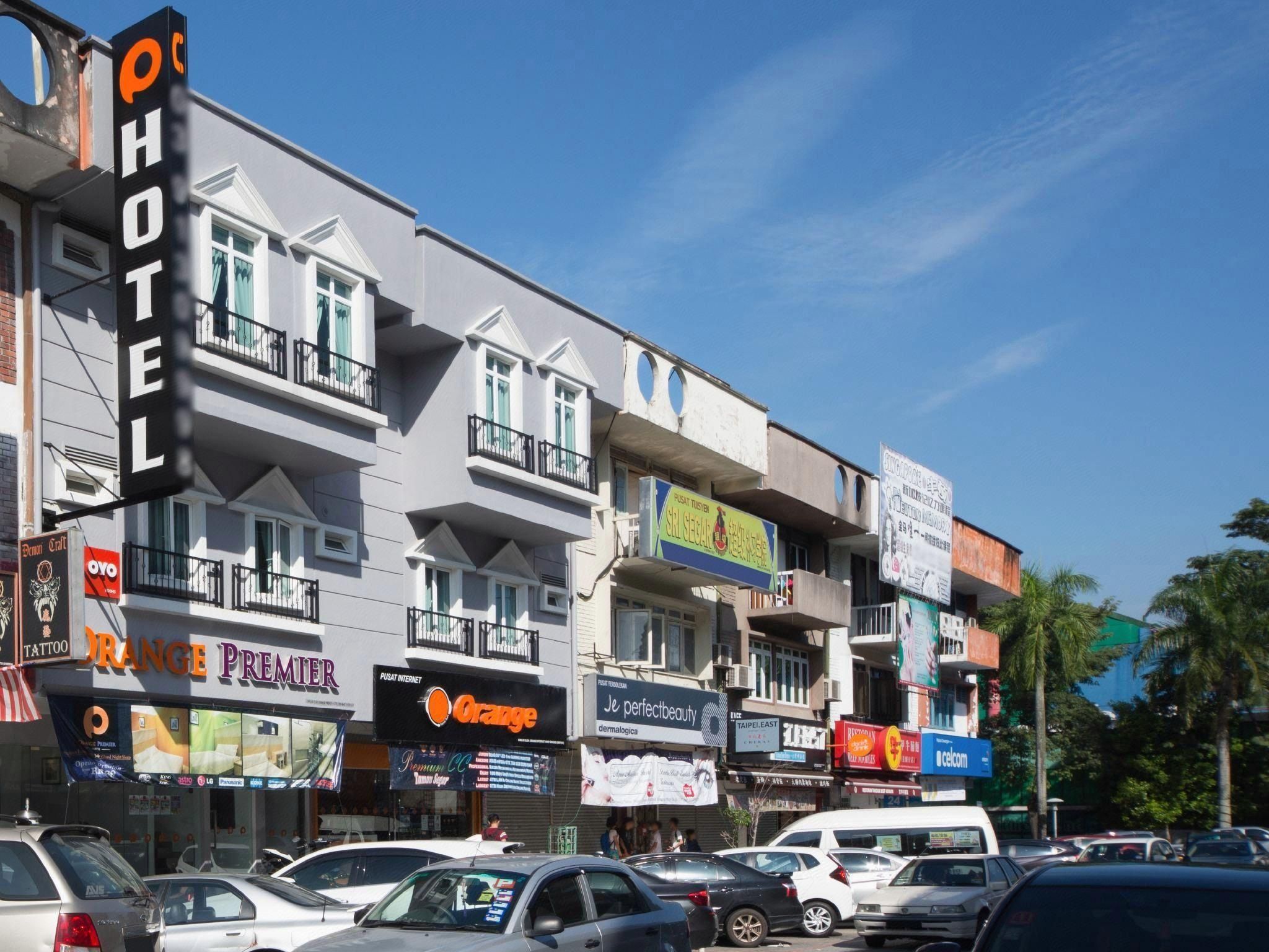 A multi-story hotel with balconies, various business signs, and parked cars.