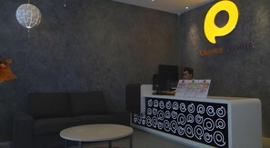 Un espace d’accueil au design moderne, comprenant un canapé, une table ronde et un écran mural affichant un logo.
