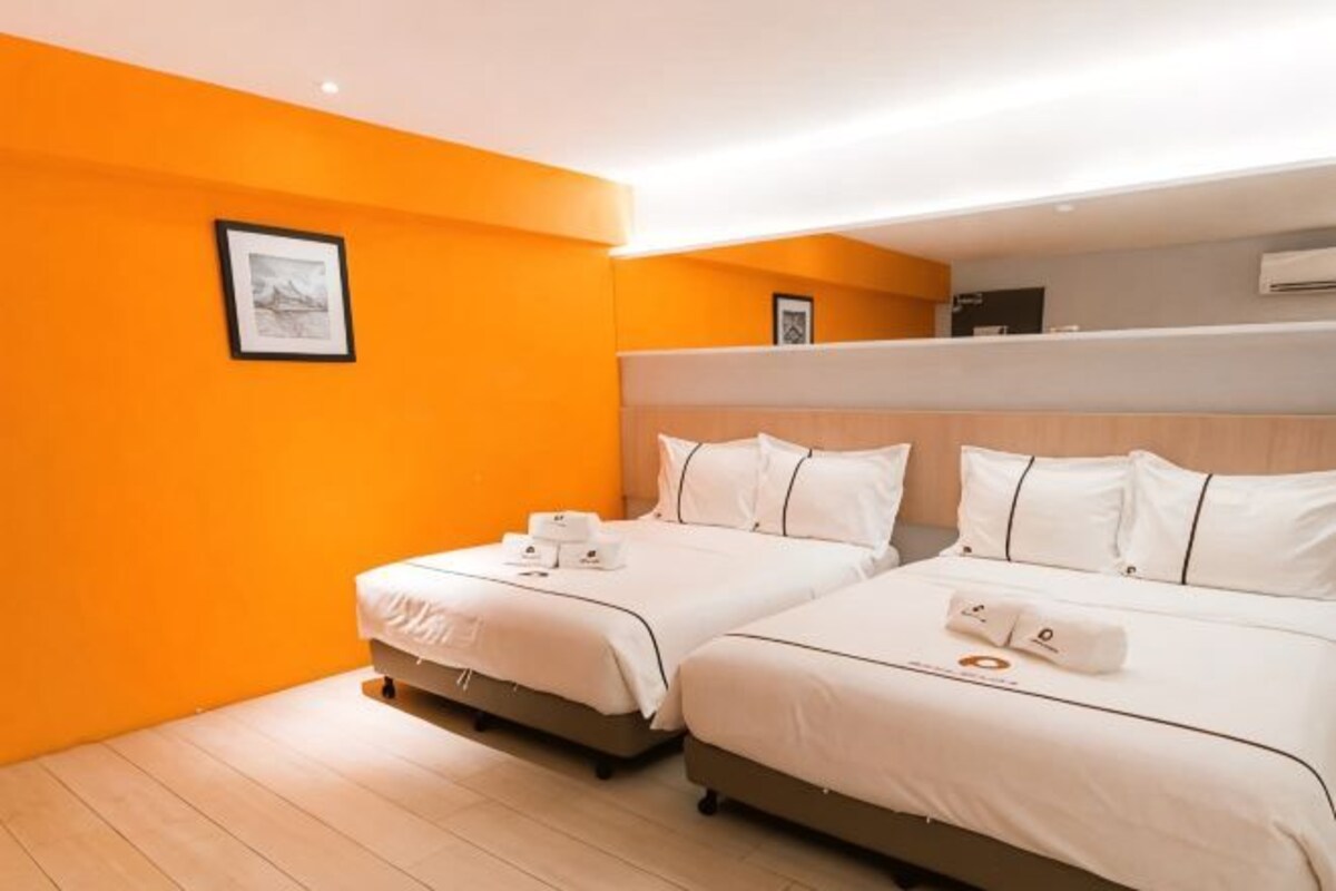 A hotel room with two beds, a wooden floor, and a framed picture on the wall.
