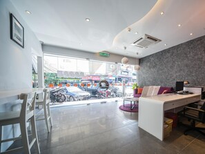 A modern reception area with a desk, chairs, and a view of parked cars outside. - Orange Premier Hotel Taman Segar (Kuala Lumpur)
