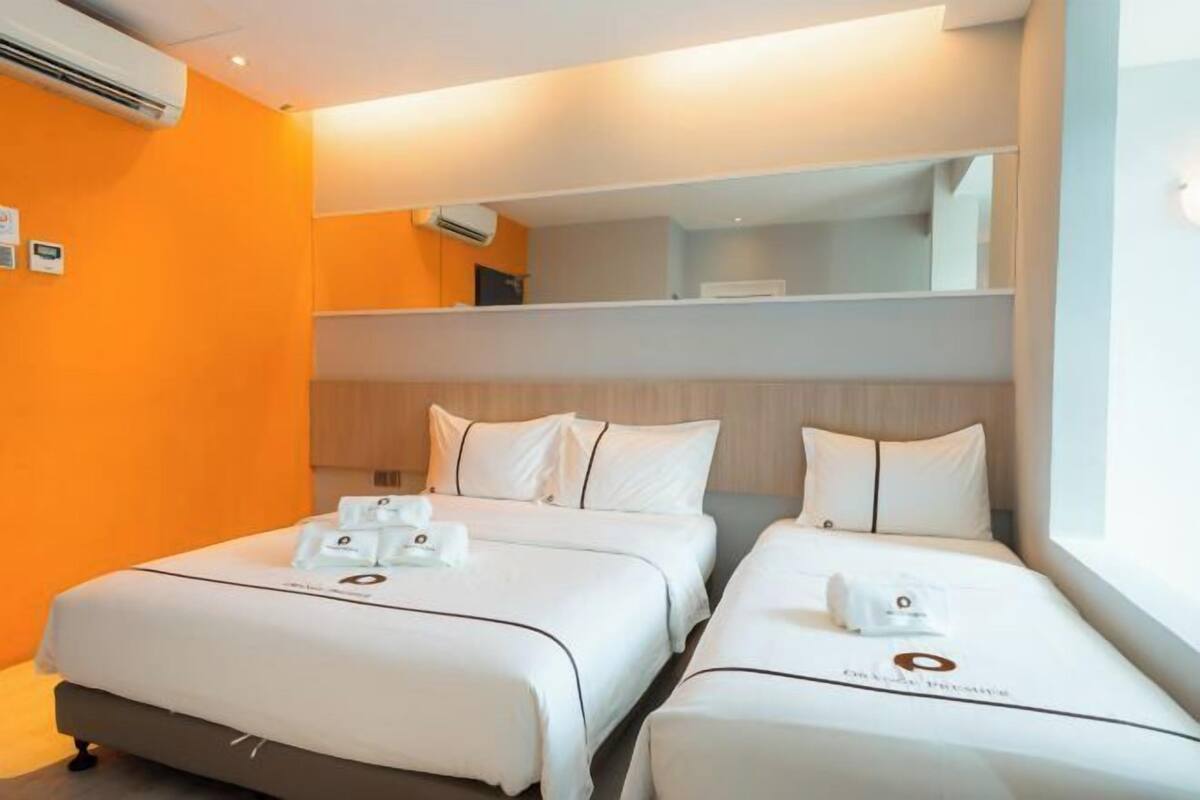 A hotel room with two beds, a minibar, and a large window.