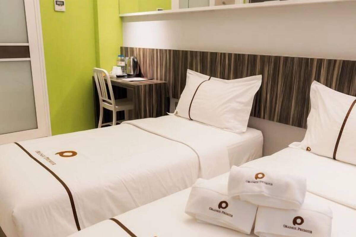 A hotel room with two beds, a desk, and a chair.