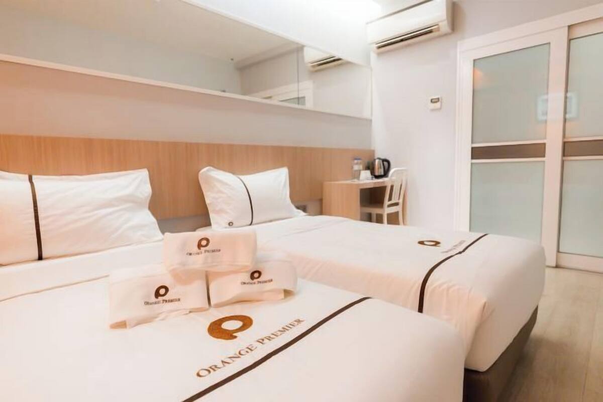 A hotel room with two beds, a desk, and a chair.