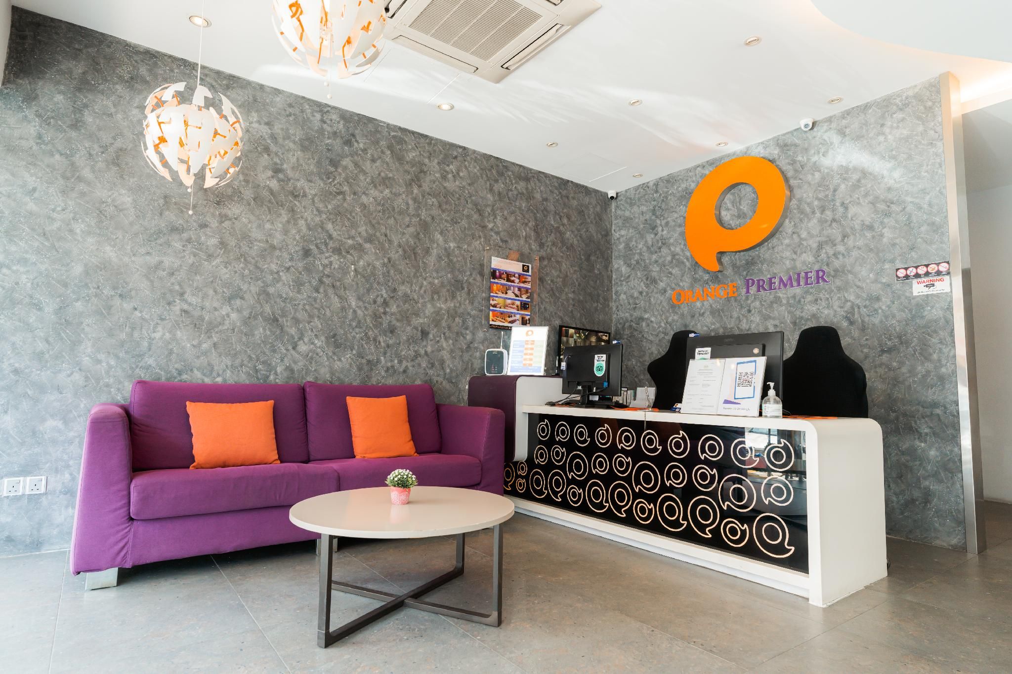 A reception area with a purple sofa, a round table, and a reception desk with a logo.