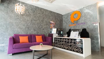 A reception area with a purple sofa, a round table, and a reception desk with a logo.