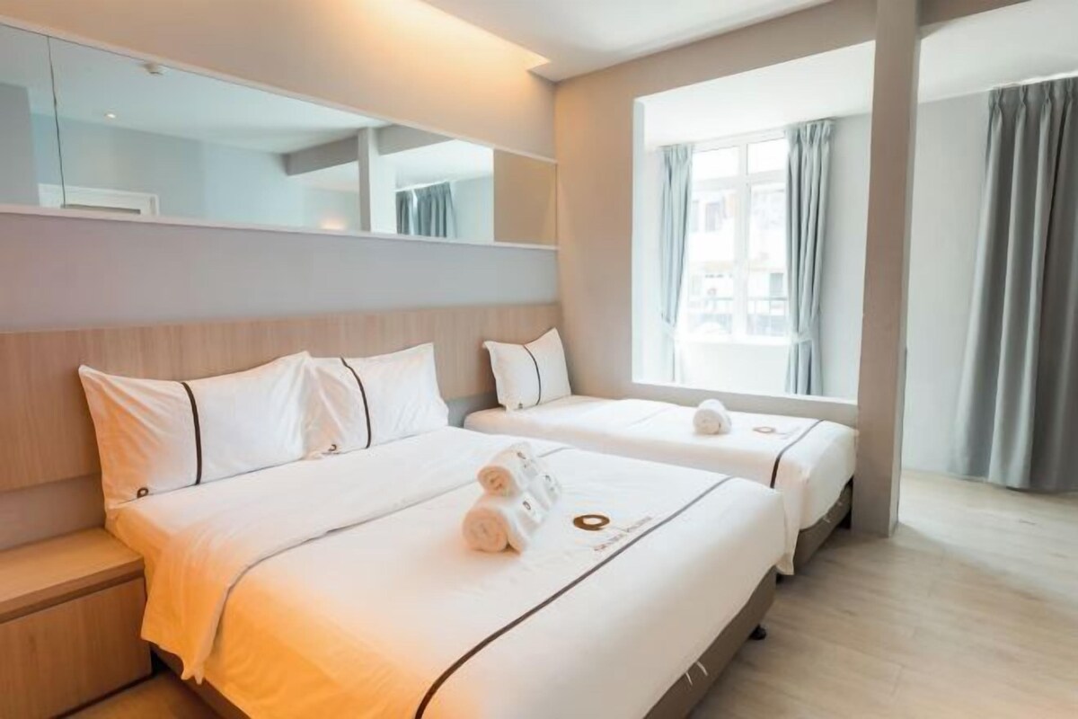 A hotel room with two beds, a large window, and a mirror above the beds.