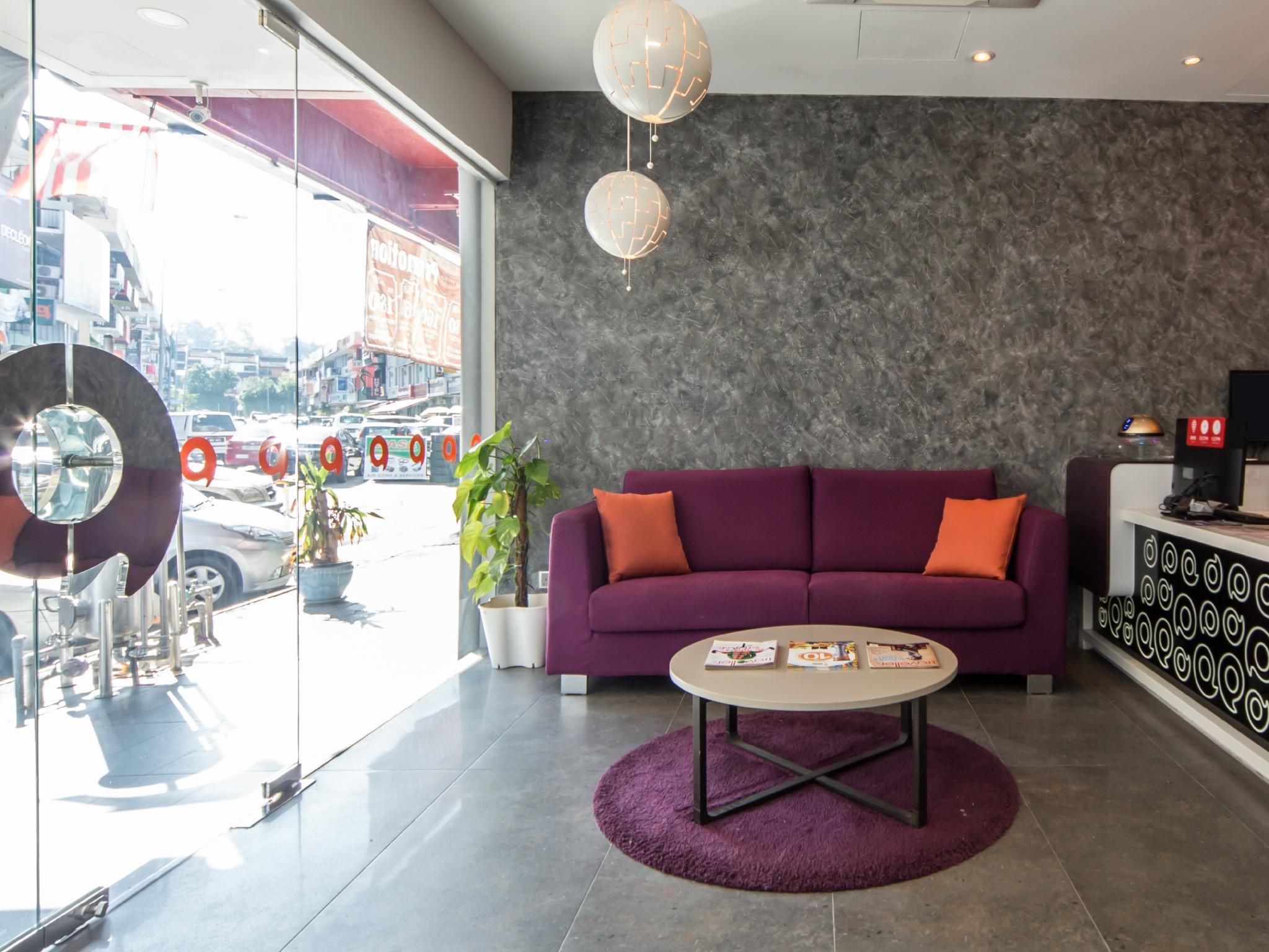 A modern interior with a purple sofa, a round coffee table, and a large mirror.