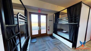A room with bunk beds, a fire extinguisher, and a view of the outdoors through a door. - Large Groups | WiFi | Wheeler Peak Lodge South (Angel Fire)