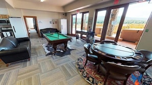 A room with a pool table, a sofa, a dining table with chairs, and a view of the outdoors. - Large Groups | WiFi | Wheeler Peak Lodge South (Angel Fire)