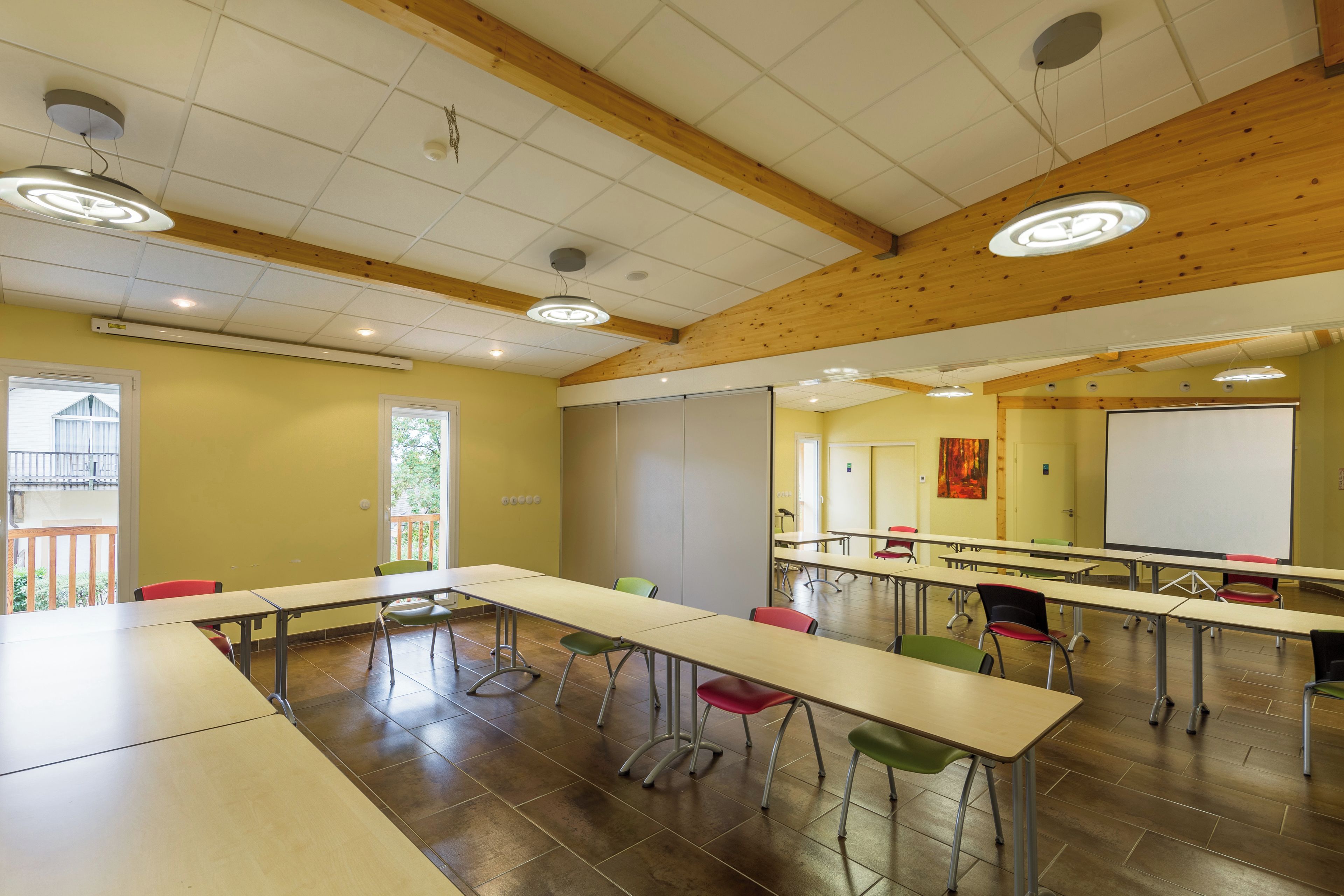 A conference room with long tables and chairs, wooden beams on the ceiling, and a whiteboard.