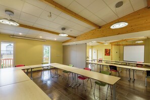 A conference room with long tables and chairs, wooden beams on the ceiling, and a whiteboard.