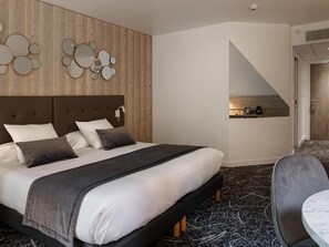A hotel room with a bed, a small kitchenette, a seating area, and a view of the outside.
