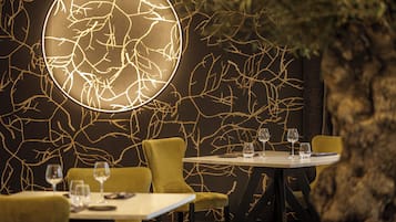 A restaurant interior with a unique wall design, a round illuminated feature, and a table set for two.
